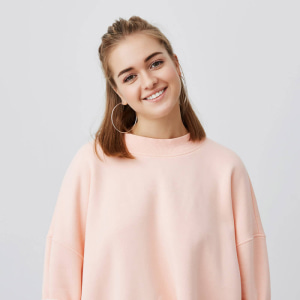 Close up shot of charming caucasian female with fair straight hair dressed in pink, gently looking , smiling while listening to interesting stories and good news. tender, beautiful, young. 